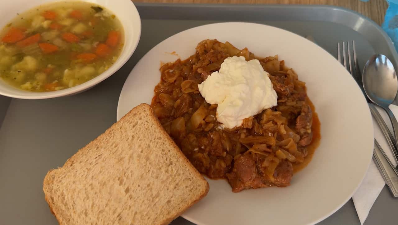 A piece of bread on the edge of a grey plate, with a pile of stew in the middle.